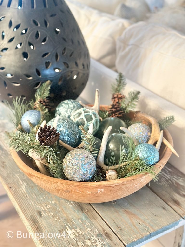 christmas balls and greens with antlers in a wood bowl