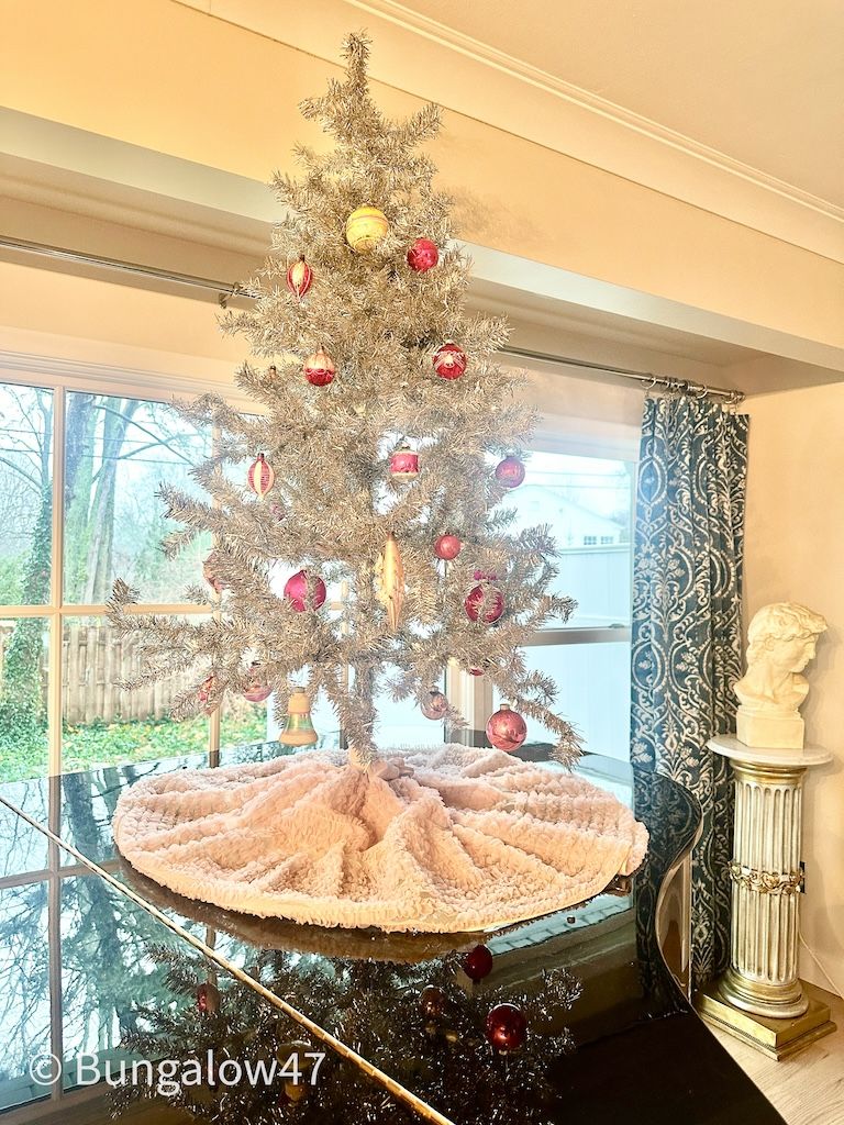 pink ruffled slip used as a Christmas tree skirt on top of a piano
